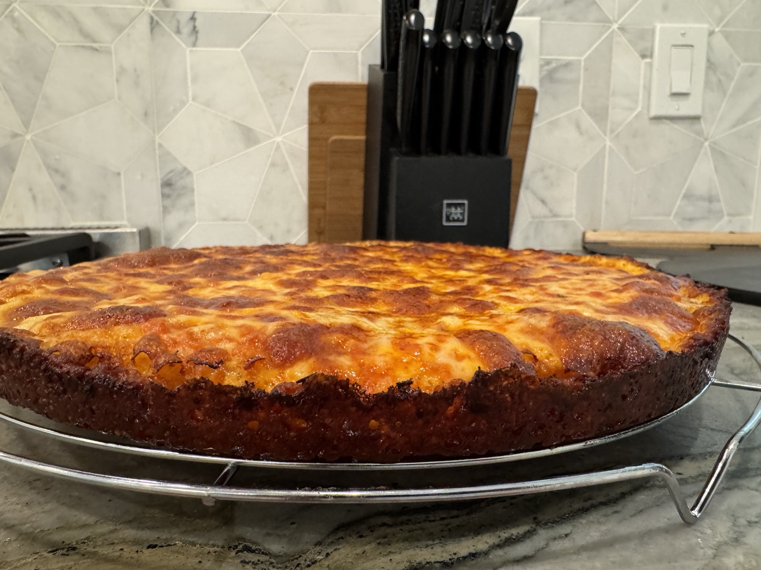 Greg’s pan pizza with a crisp cheese edge, cooling on a rack
